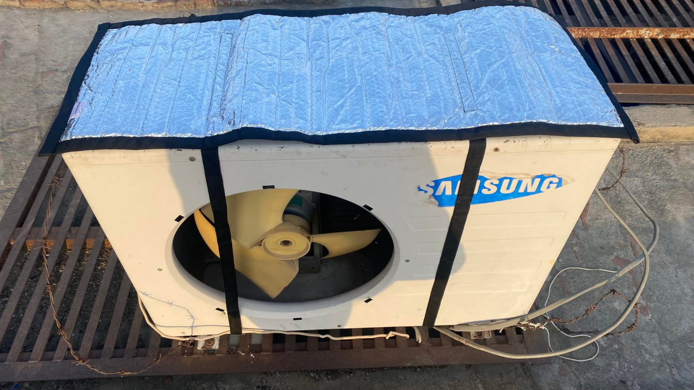 A Samsung outdoor air conditioner or heat pump unit with a white cabinet, visible fan blades inside the front circular opening, and a light blue protective cover draped over the top. The unit is photographed outdoors on a metal grate over concrete.