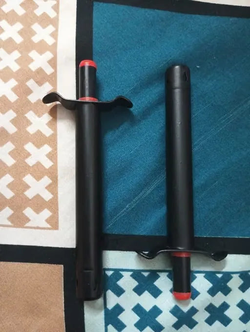 Two black training darts with red tips and red collar accents, displayed on a patterned teal and beige rug.