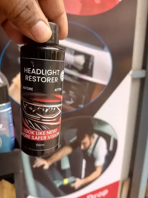 A hand holding a small black bottle labeled 'HEADLIGHT RESTORER' in front of a printed product poster.