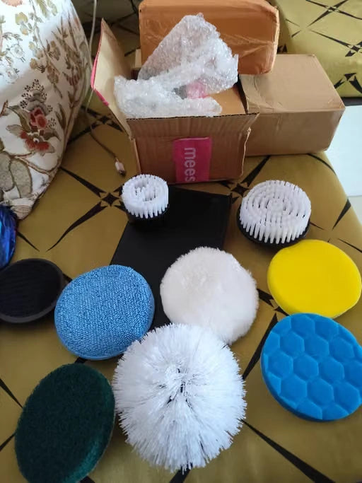 A set of car waxing and polishing brushes and pads by Meebs, displayed on a patterned gold and black tablecloth with cardboard shipping boxes in the background.