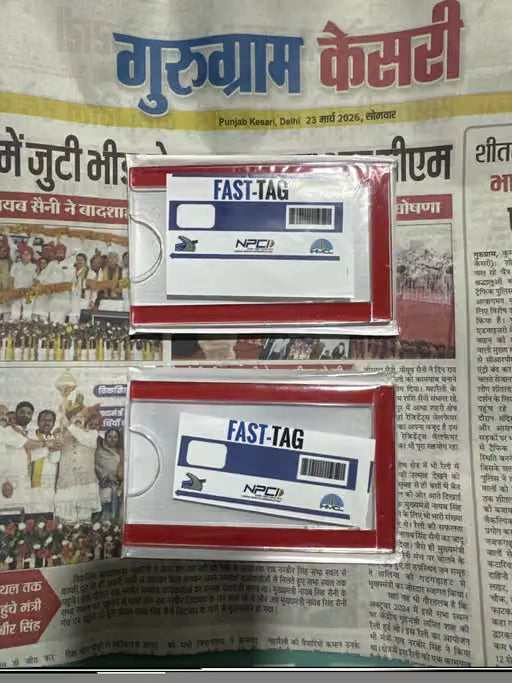 Two NPCI Fast-Tag cards in red and white packaging, stacked on top of a newspaper with Hindi text.