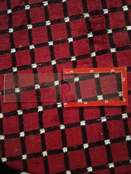 A clear plastic sleeve with a small cutout and a red backing card, placed on a red, black, and white plaid fabric background.