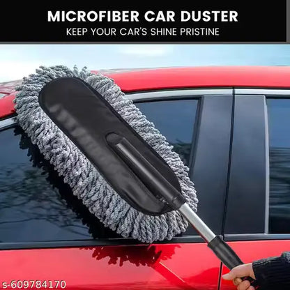 A gray microfiber car duster with a black handle and silver extension pole being used to clean the side window of a red car. A hand is holding the duster, and a black banner at the top reads 'MICROFIBER CAR DUSTER KEEP YOUR CAR'S SHINE PRISTINE'.