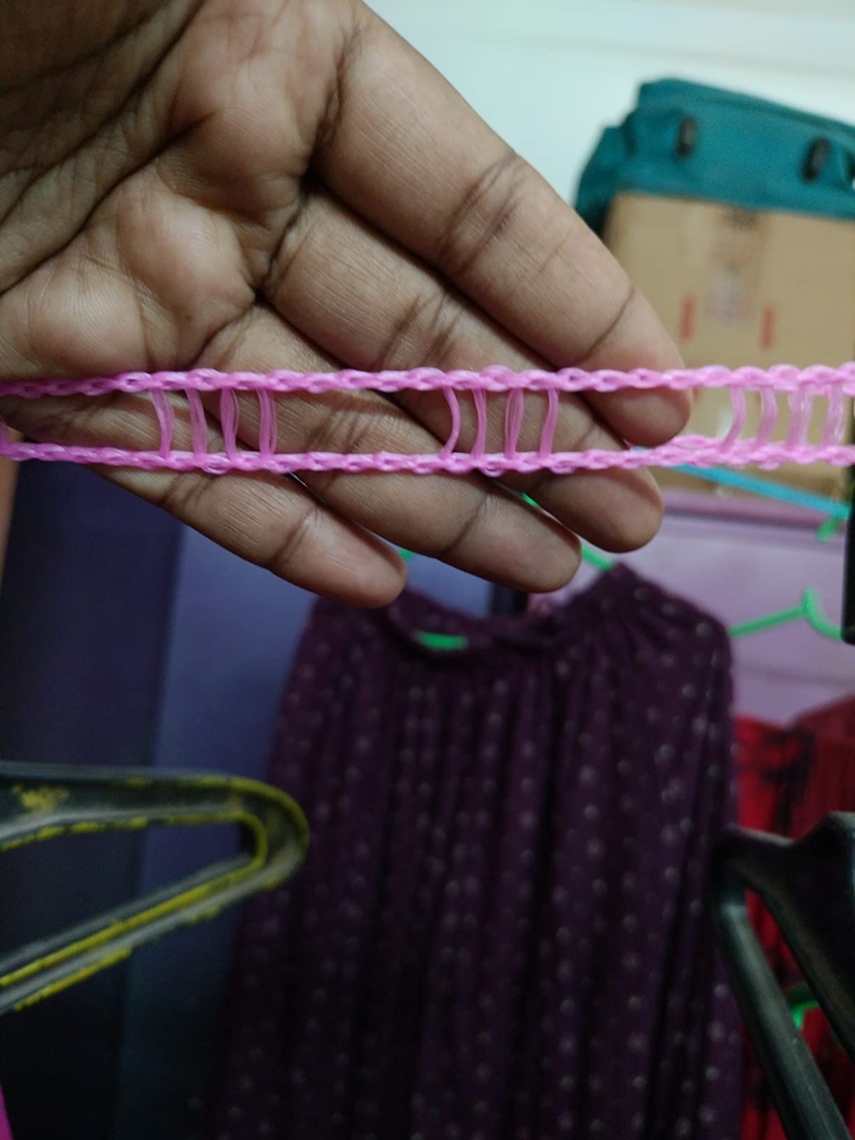 Hand holding a pink chain with a blurred background