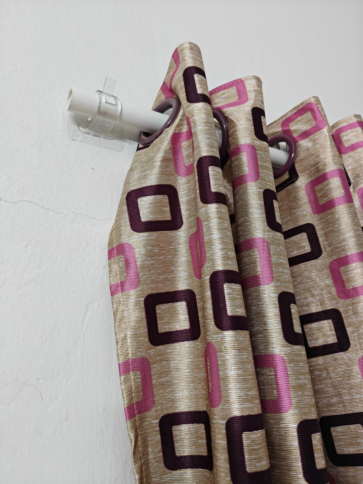 Curtains with geometric pattern hanging on a rod against a white wall
