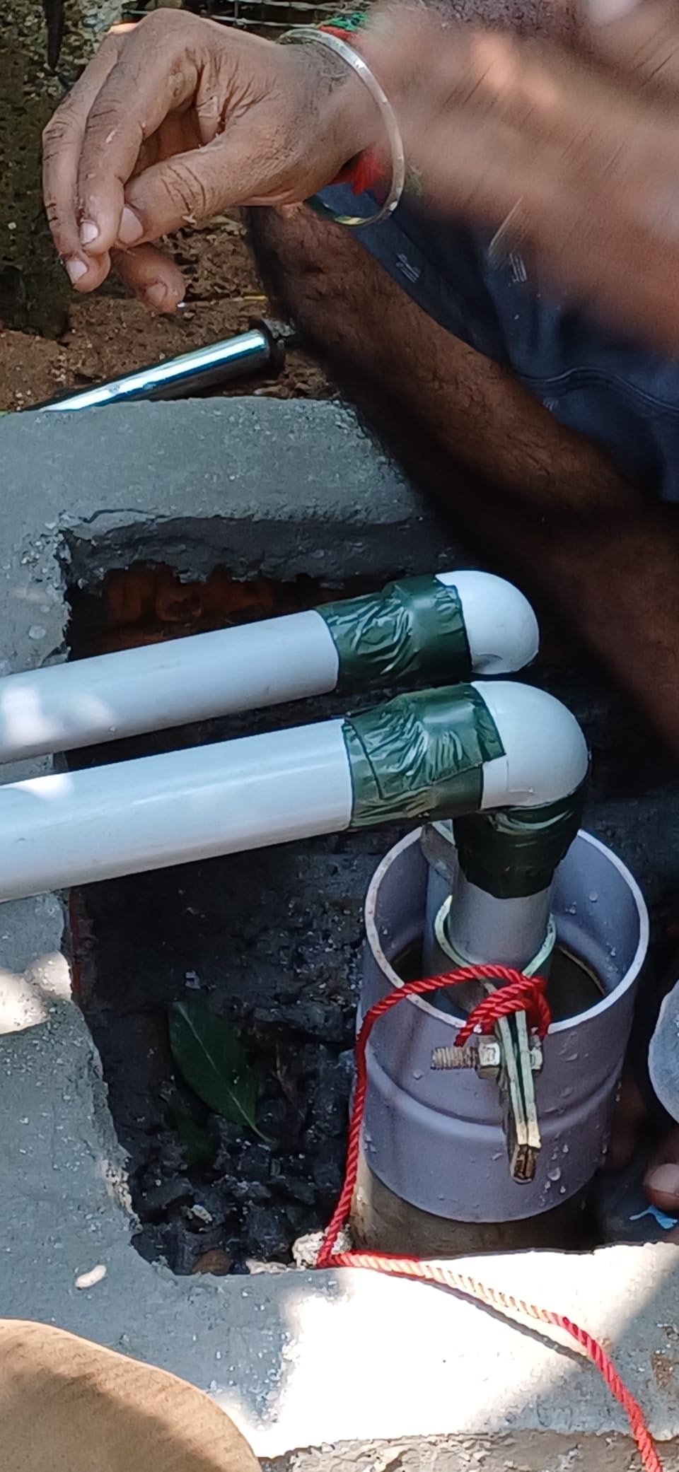 Person working with white pipes and tools on a concrete surface